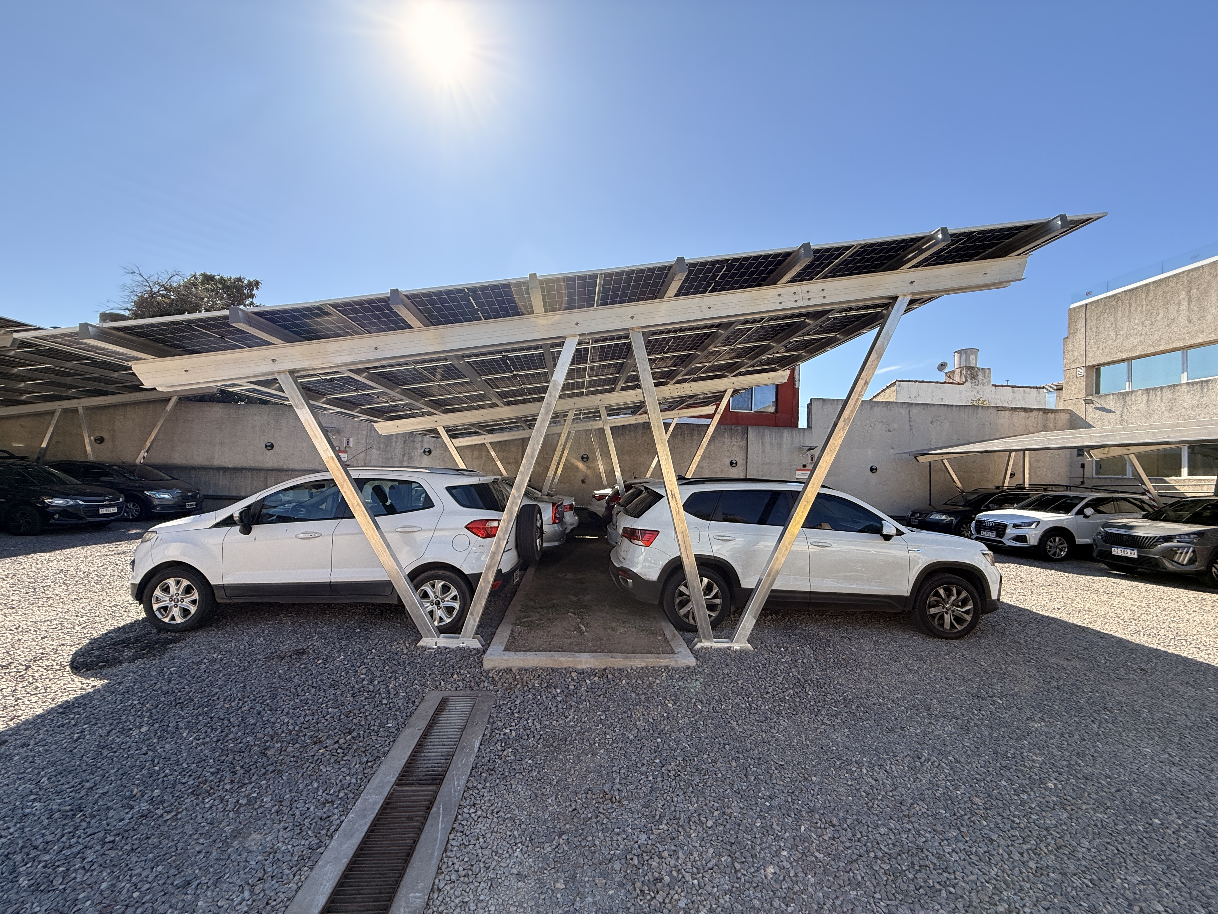 Estructura carport solar en operación: sombra para los vehículos, generación para el establecimiento y piedra nueva en el suelo para maximizar el albedo de los paneles bifaciales.