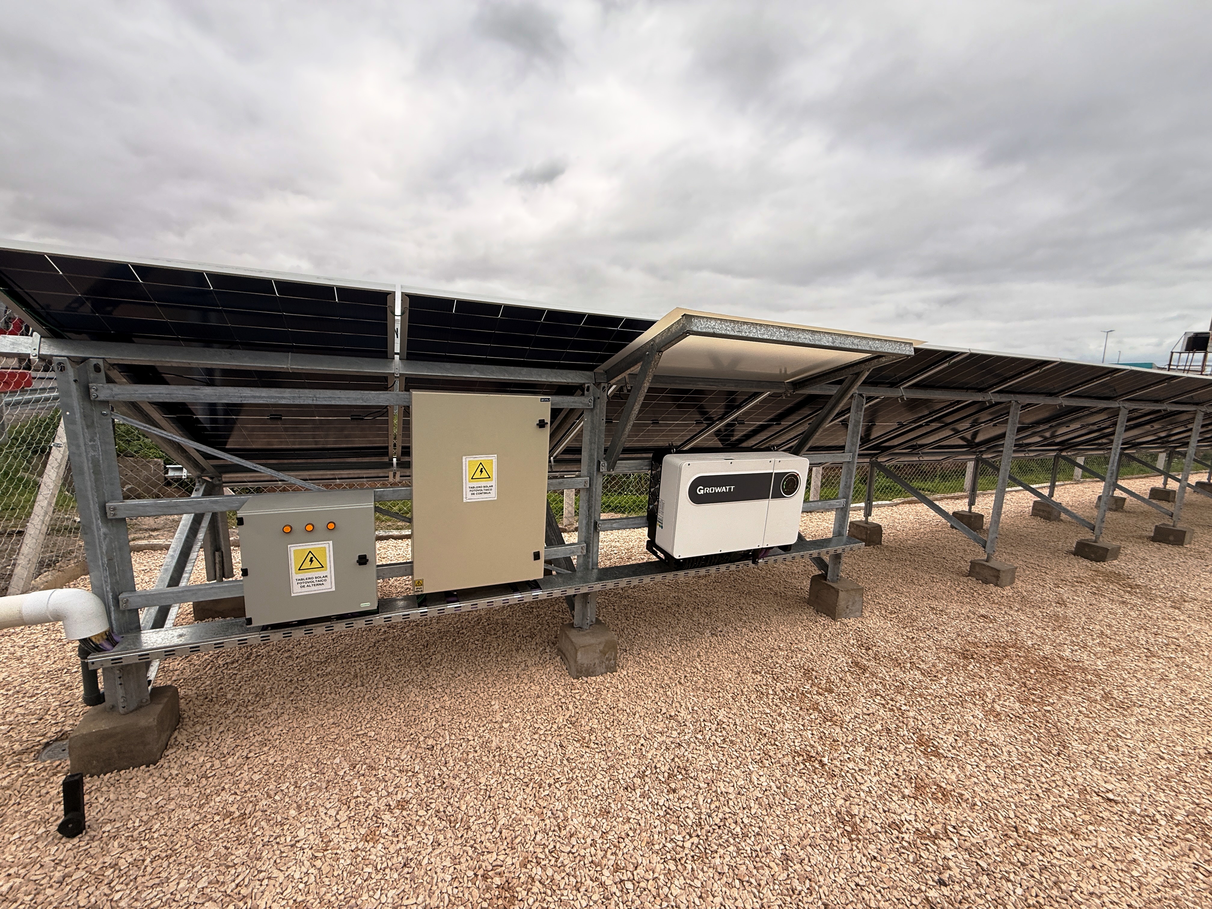 Inversor Growatt de 80 kW y tableros DC y AC montados bajo la estructura Tonka, ocultos desde la autopista por los propios paneles solares: ingeniería que no ocupa espacio adicional en el predio.
