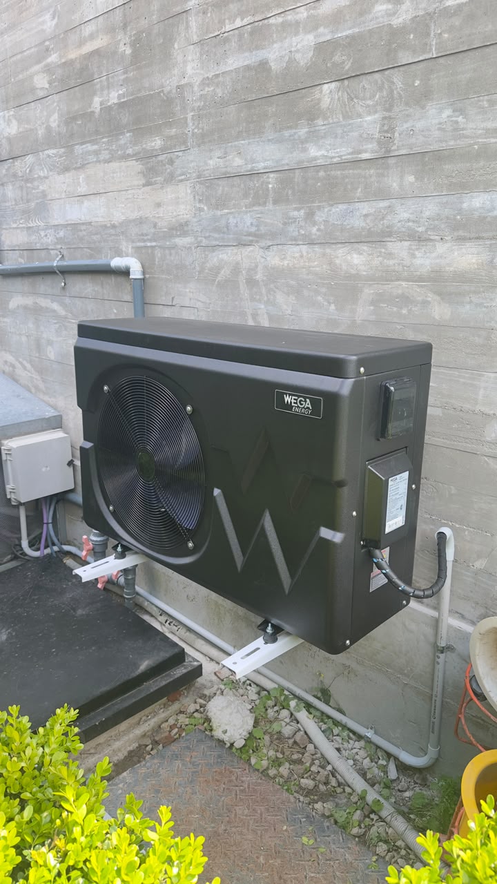 Bomba de calor inverter de 17 kW sobre ménsulas, integrada al hormigón visto y a la sala técnica del jardín.